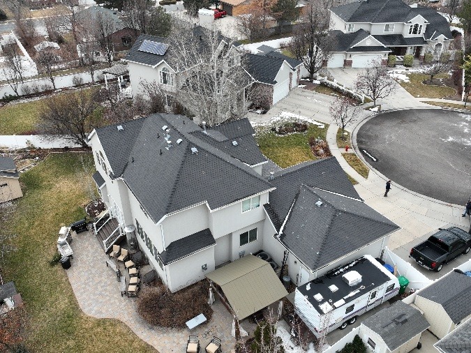 Overhead shot of a house with a driveway and a car parked nearby.